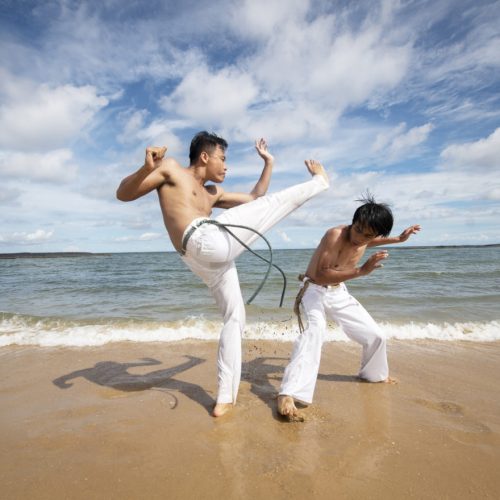 men-by-beach-practicing-capoeira-together